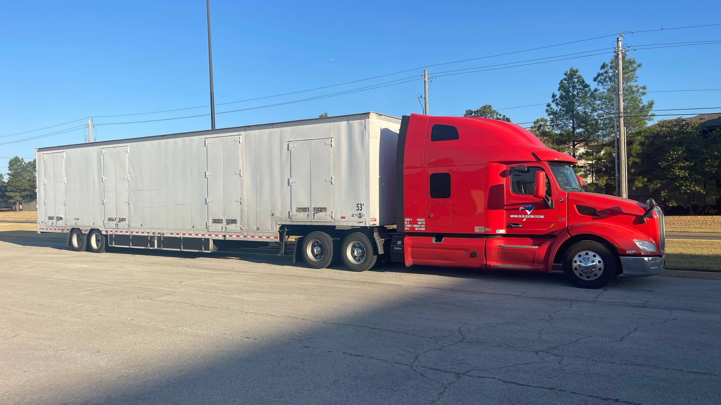 Moving On Relocation Systems red semi truck pulling a 53-foot white moving trailer